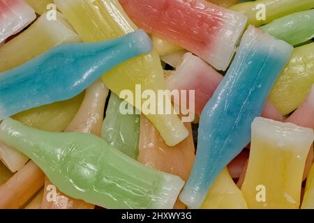 Wachsflaschen Süßigkeiten mit verschiedenen Farben und Geschmacksrichtungen verstreut. Direkt über flachem Lay-Makro. Stockfoto