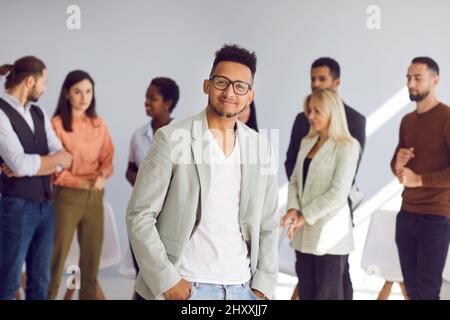 Porträt eines jungen Geschäftsführers, der vor seinem vielfältigen Geschäftsteam steht Stockfoto