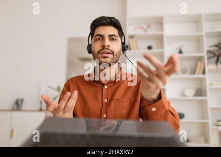 Arabischer Mann mit Laptop und Headset am Schreibtisch Stockfoto