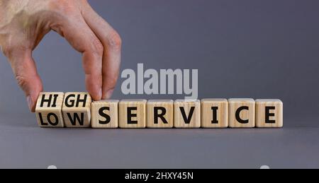 Symbol für niedrigen oder hohen Service. Geschäftsmann dreht Würfel und ändert Wörter niedrigen Service zu hohem Service. Schöne graue Tabelle grauen Hintergrund. Geschäftsniedrig Stockfoto