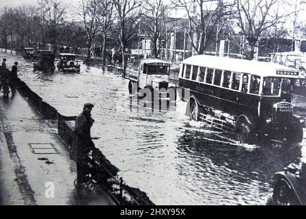 Ein Pressefoto aus den 1930er Jahren von Überschwemmungen auf der Great Bath Road in Maidenhead, Großbritannien. Der alte Bus fährt nach Slough Stockfoto