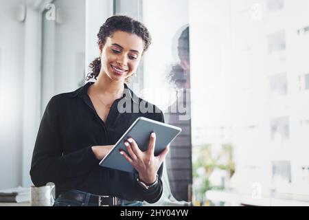 Verwalten Sie ihre täglichen Aufgaben mit den intelligentesten Apps. Aufnahme einer jungen Geschäftsfrau, die in einem Büro ein digitales Tablet benutzt. Stockfoto