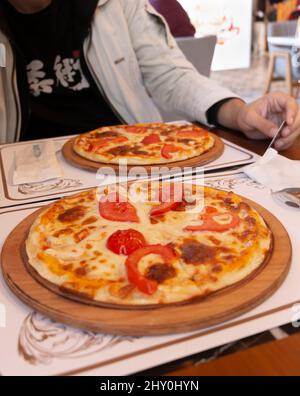 Eine frisch gebackene Pizza Margherita mit Olivenöl, Tomaten, Mozzarella und Basilikum. Stockfoto