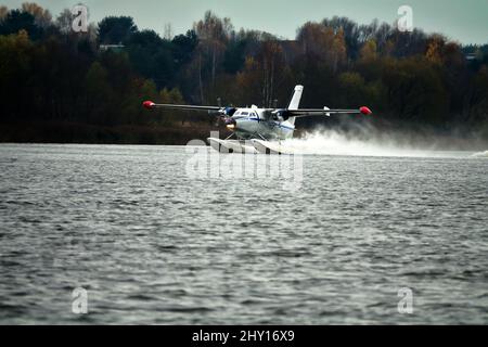 Das zweimotorige Wasserflugzeug ein Wasserflugzeug steigt aus dem Wasser, aus dem Waldsee, dem nördlichen Land auf. Wasserflugzeug Stockfoto