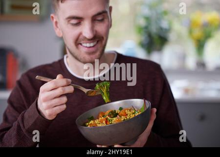 Close Of Man Eating Healthy Vegan Lunch In Kitchen At Home Stockfoto