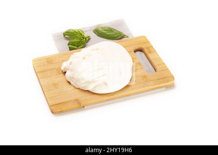 Holzdiele mit Käse und grünen Basilikumblättern isoliert auf weißem Hintergrund Stockfoto