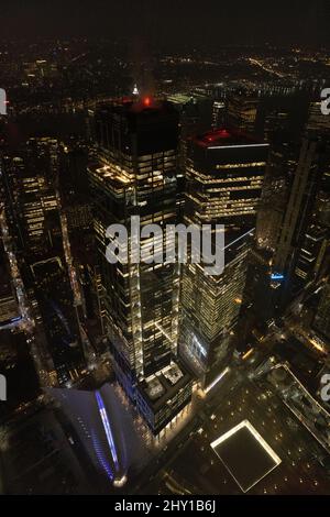 Über den modernen Hochhäusern mit leuchtenden Lichtern in der dunklen Straße von New York City bei Nacht Stockfoto
