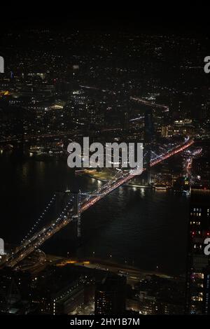 Von oben die leuchtende Brücke über den Fluss in New York City mit modernen, glänzenden Gebäuden in der Nacht in New York City Stockfoto