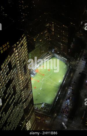 Von oben auf dem grünen Baseballfeld mit weißen Linien in der Nähe eines modernen Gebäudes in der Nacht in New York City Stockfoto