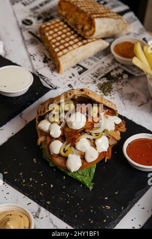 Von oben appetitliche griechische Gyros mit Mozzarella-Käse und grünen Oliven serviert auf dem Tisch mit leckeren Shawarma in der Küche Stockfoto