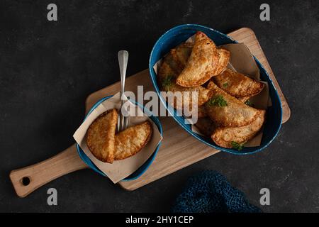 Draufsicht köstliche Teller mit Knödeln und Empanadas auf einem schwarzen Tisch in einer Küche Stockfoto