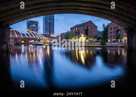 Der Blick auf das Castlefield-Abendprogramm umrahmt von einer Brücke entlang des Flusses Irwell in Manchester, England Stockfoto