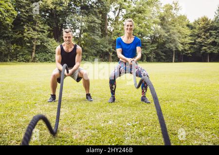 Junger Mann und junge Frau trainieren mit Kampfseil Stockfoto