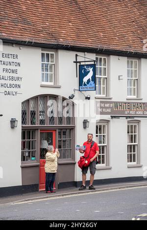 Das White Hart Inn oder Pub mit Postboten, die Post im Zentrum von Overton Village, Hampshire, England, Großbritannien, liefern Stockfoto