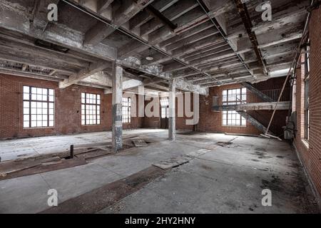 In einem leeren, geräumigen, dreckigen, verlassenen Industriegebäude mit abblätternder Farbe und anziehenden Bodenfliesen Stockfoto