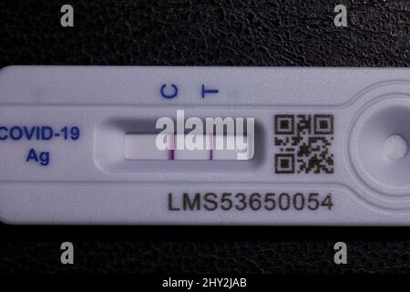 Positiver Covid 19 Lateral Flow Test / Rapid lateral Flow Antigen Coronavirus Test auf schwarzem Hintergrund mit beiden Balken auf dem Teststreifen Stockfoto