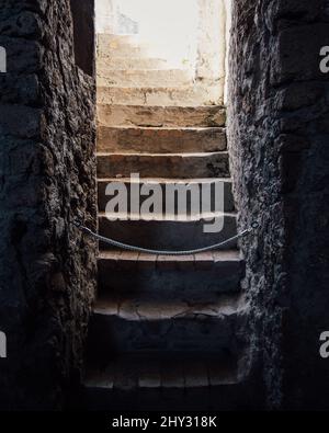 Blick auf eine alte Steintreppe, die mit einem Seiltor mit Wänden von beiden Seiten geschlossen ist Stockfoto