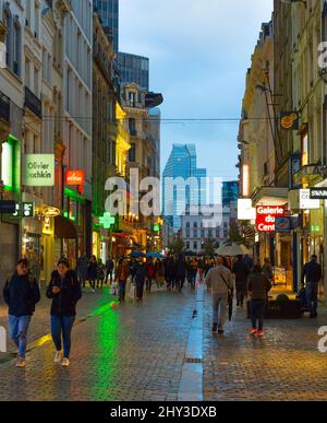 BRÜSSEL, BELGIEN - 06. OKTOBER 2019: Menschenmenge, die in der Dämmerung an der Einkaufsstraße der Altstadt von Brüssel spazieren Stockfoto