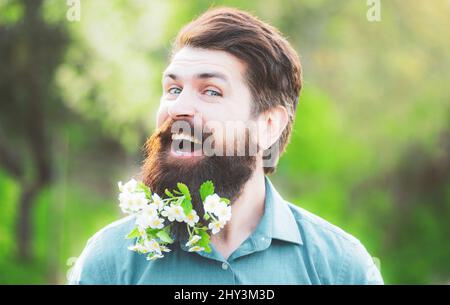 Blütenbart. Bärtiger Mann mit Frühlingsblumen im Bart. Stockfoto