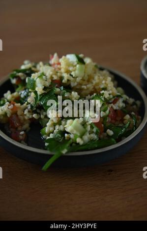 Vertikale Aufnahme eines Salats mit Couscous und Gemüse in einer Schüssel auf dem Tisch Stockfoto