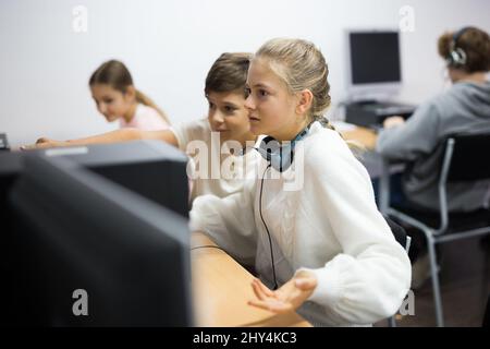 Junge helfen verärgert Mädchen, um Problem auf dem Computer in der Schulklasse zu lösen Stockfoto