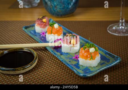 Köstlicher Premium-Lachs- und Thunfisch-Oshizushi-Sushi (Biera-Sushi) auf einem dekorierten handgefertigten Porzellanteller. Stockfoto