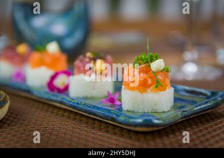 Köstlicher Premium-Lachs- und Thunfisch-Oshizushi-Sushi (Biera-Sushi) auf einem dekorierten handgefertigten Porzellanteller. Stockfoto