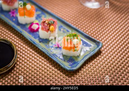 Köstlicher Premium-Lachs- und Thunfisch-Oshizushi-Sushi (Biera-Sushi) auf einem dekorierten handgefertigten Porzellanteller. Stockfoto