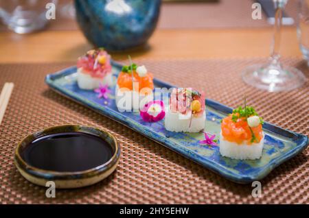 Köstlicher Premium-Lachs- und Thunfisch-Oshizushi-Sushi (Biera-Sushi) auf einem dekorierten handgefertigten Porzellanteller. Stockfoto