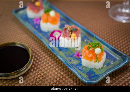 Köstlicher Premium-Lachs- und Thunfisch-Oshizushi-Sushi (Biera-Sushi) auf einem dekorierten handgefertigten Porzellanteller. Stockfoto