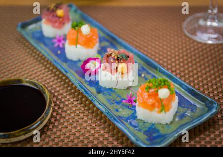 Köstlicher Premium-Lachs- und Thunfisch-Oshizushi-Sushi (Biera-Sushi) auf einem dekorierten handgefertigten Porzellanteller. Stockfoto