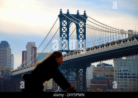 Fahrradfahrer, der unter der Manhattan Bridge vorbeifährt, die vom südlichen Manhattan nach Brooklyn führt Stockfoto