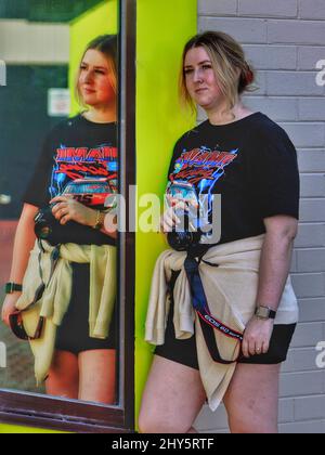 Die australische Fotografin lehnt sich an eine Wand und reflektiert auf einem Spiegel Stockfoto