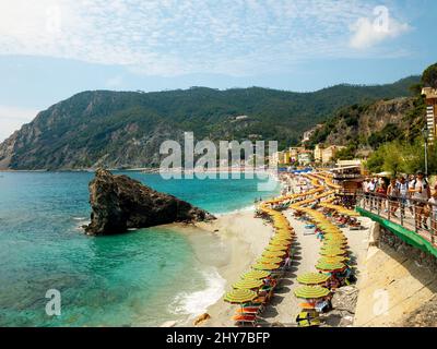 Luftaufnahme von Dutzenden von Liegestühlen und Sonnenschirmen an der sandigen Küste ein sonniger Tag in Cinque terre Stockfoto