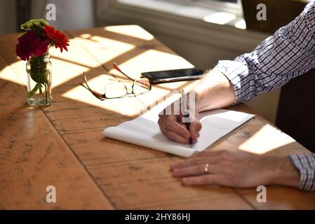 Nahaufnahme einer erwachsenen Frau, die einen Stift hält und etwas aufschreiben will Stockfoto