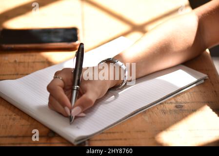 Nahaufnahme einer erwachsenen Frau, die einen Stift hält und etwas aufschreiben will Stockfoto