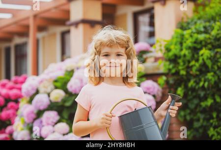 Kind Junge wässern Pflanzen im Garten mit Gießkannen. Die Welt grün machen. Sommerlandwirtschaft. Stockfoto