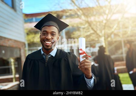 Meine Erfolgsgeschichte beginnt hier. Porträt eines glücklichen jungen Mannes, der am Abschlusstag ein Diplom hält. Stockfoto