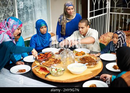 Dig in jeder. Aufnahme einer muslimischen Familie, die zusammen isst. Stockfoto