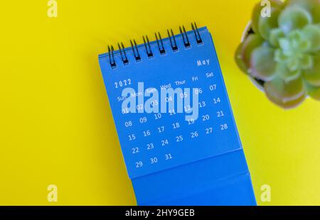 Blauer Desktop-Kalender für Mai 2022 für die Planung auf gelbem Hintergrund Stockfoto