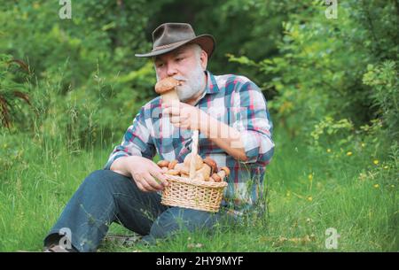 Glücklicher Großvater - Sommer und Hobbys. Opa Rentner. Großvater mit einem Korb von Pilzen und einem überraschenden Gesichtsausdruck. Stockfoto