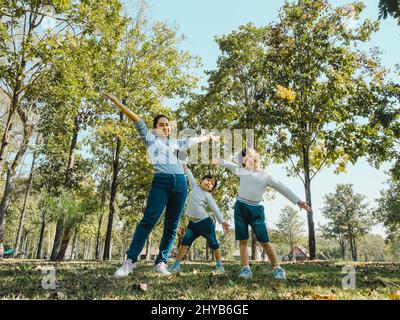 Zwei niedliche kleine asiatische Mädchen in Sommer-Outfits, Spaß mit einer schönen jungen Mutter lächeln glücklich im Park. Mutterschaft und Familienkonzept. Stockfoto