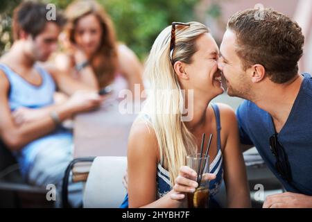 Wahre Liebe. Junge Teenager-Paar lachen und über zu küssen, während aus mit Freunden. Stockfoto