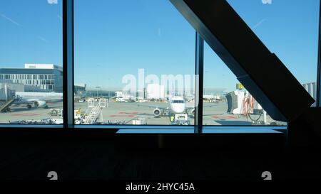 Blick auf die Start- und Landebahn des San Francisco International Airport vom Inneren des Terminals 2; Fensterscheibe, Flugzeuge und Mitarbeiter, die arbeiten; SFO. Stockfoto