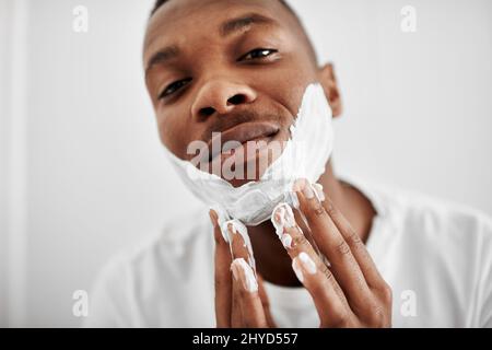 Ich rasur es lieber alle. Kurzer Schuss eines jungen Mannes, der Rasierschaum auf sein Gesicht auftragen soll. Stockfoto