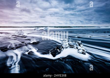 Große Stücke des Eisbergs, die auf dem schwarzen Sand funkeln. Beliebte Touristenattraktion. Lage berühmter Ort Jokulsarlon Lagune, Vatnajokull National Stockfoto