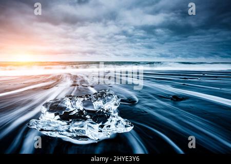 Große Stücke des Eisbergs, die auf dem schwarzen Sand funkeln. Beliebte Touristenattraktion. Lage berühmter Ort Jokulsarlon Lagune, Vatnajokull National Stockfoto