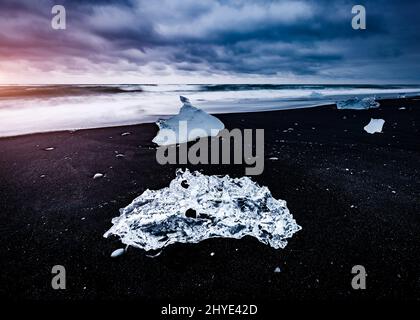 Große Stücke des Eisbergs, die auf dem schwarzen Sand funkeln. Beliebte Touristenattraktion. Lage berühmter Ort Jokulsarlon Lagune, Vatnajokull National Stockfoto