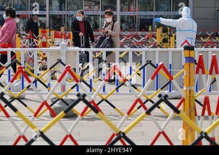 YANTAI, CHINA - 15. MÄRZ 2022 - Mitarbeiter zur Epidemien-Prävention führen ausreisende Passagiere zur Entnahme von Nukleinsäuretestproben am Yantai-Bahnhof in Stockfoto