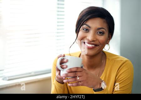 Tee ist für die Seele. Eine kurze Aufnahme einer attraktiven jungen Frau, die allein sitzt und in ihrem Haus eine Tasse Tee trinkt. Stockfoto
